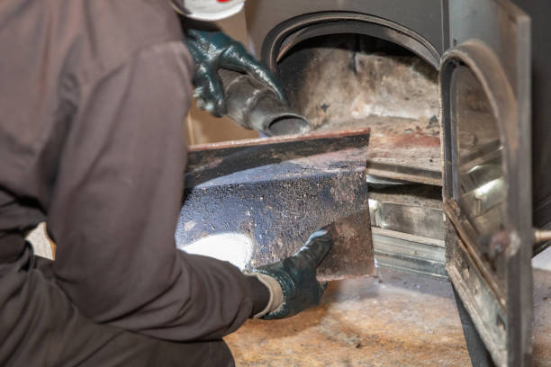 Chimney sweep removing the plate in a modern log burner - cleaning the chimney.